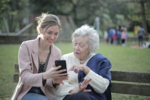 en kvinna och en äldre dam tittar på en skärm i en park