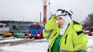 Kvinna med hjälm, hijab och arbetskläder på byggarbetsplats