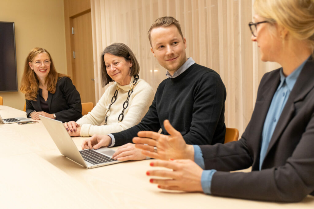 tre kvinnor och en man vid ett konferensbord i möte